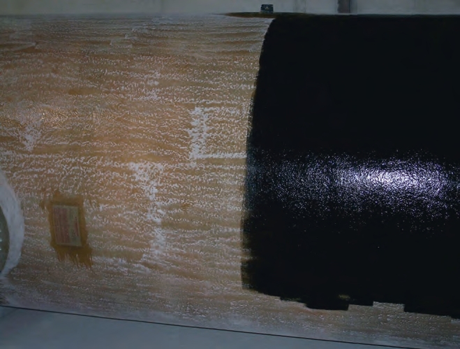 A tank receives a gel coat. To the left of the black paint, you can see how the fiberglass was lightly ground to help the gel coat bond to the finished tank. 