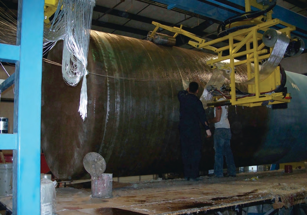 In this photo, the blue cylinder is the mold and the fiberglass tank being formed is brown. When complete, this tank will measure 10 feet wide, 15 feet tall, and hold 8,800 gallons.
