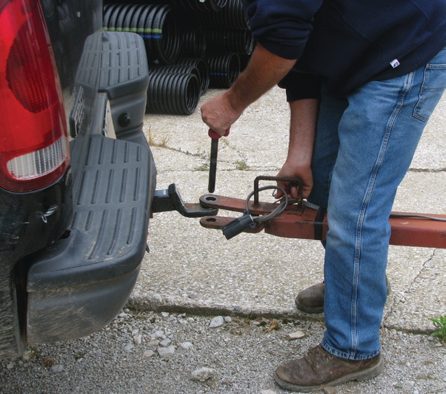 man putting hitch pin to a trailer truck