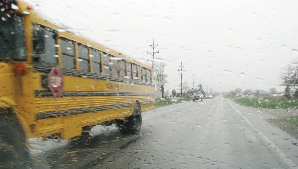 trailer unhitched from a tractor and school bus is passing by on the road