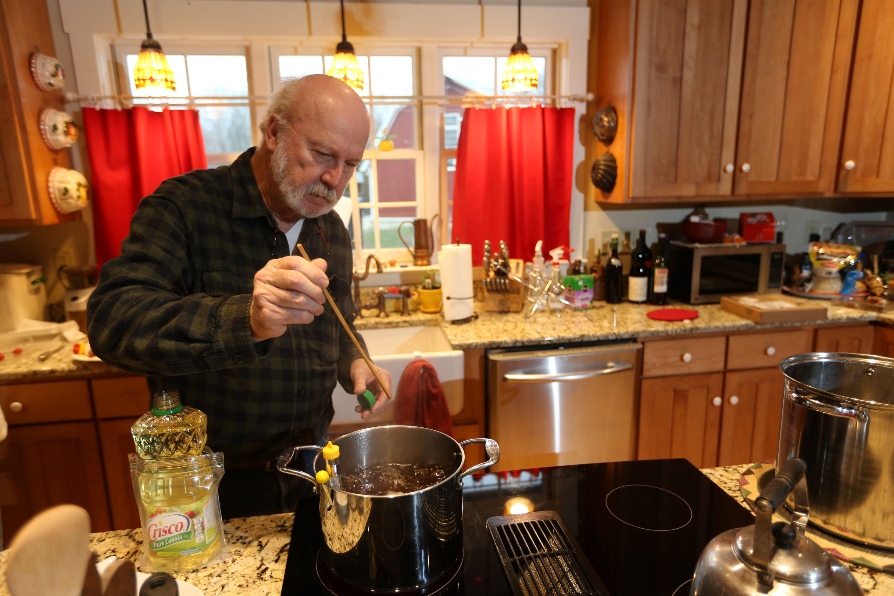 Man standing by stovetop while boiling syrup in a pot