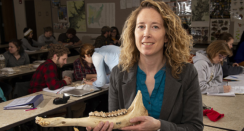 Dr. Liz Flaherty holding jawbone with students identifying other jawbones in the background.