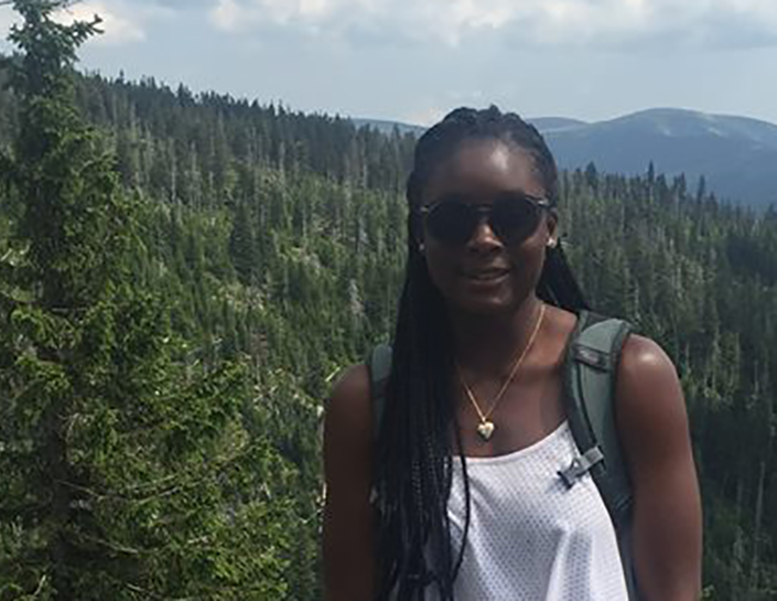 Kendra Huff received funds to study abroad, standing in forest with mountains in background.