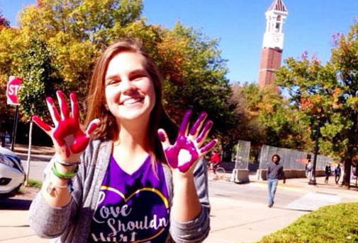 Grace Weisenbach, aquatic sciences student, outside at Purdue with paint on hands showing her Purdue Boilermaker pride.