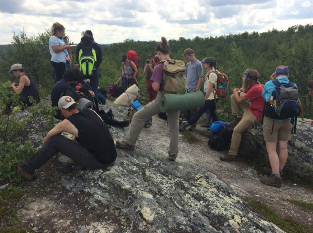 Study Abroad trip to Sweden, students sitting on rocks with mountains in background.