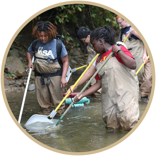 Aquatic Ecosystems Manager and students in river with wade waters on.