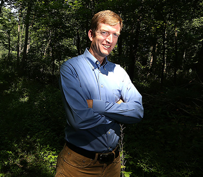 Dr. Jeff Dukes poses in front of a forest