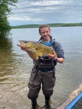 Amara Brenton holds a fish while standing in a river.