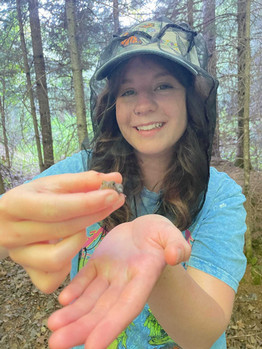 Dani Hoffman shows a small frog to the camera.