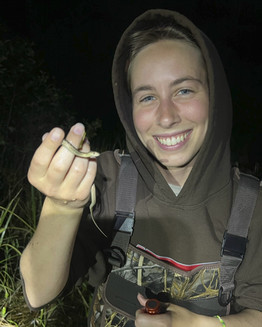 Lauren Toepp shows a snake to the camera.