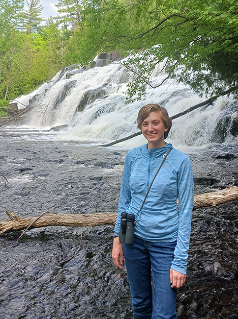 Lydia Pultorak in a lake in front of a waterfall