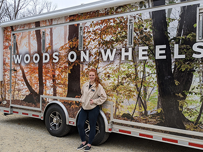 Alumna Sara High poses with the Woods on Wheels exhibit trailer