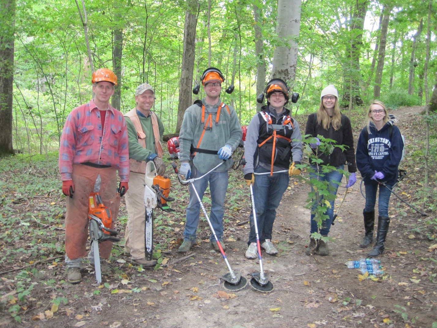 Group with chainsaws and industrial trimmers helping control invasives.