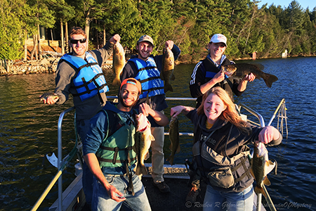 Students at Summer Practicum on boat with holding five caught fish.