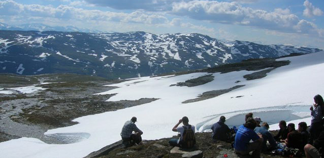 Study Abroad trip to Sweden, students sitting in snow on mountains.