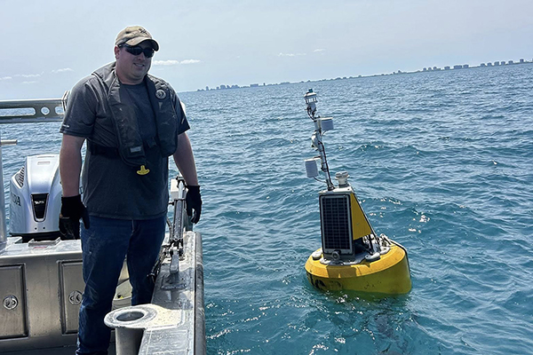 Illinois-Indiana Sea Grant buoy in Great Lakes with staff member in boat.