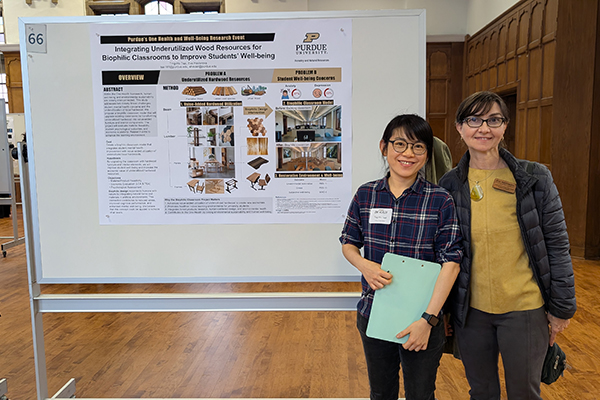 Student standing by poster and Dr. Eva Haviarova  with biophilia research, wood products.