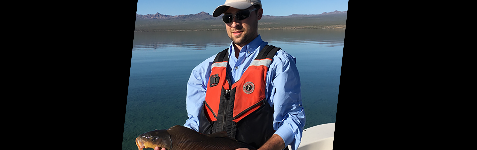 Wes Goldsmith, FNR alumni, on boat holding a fish