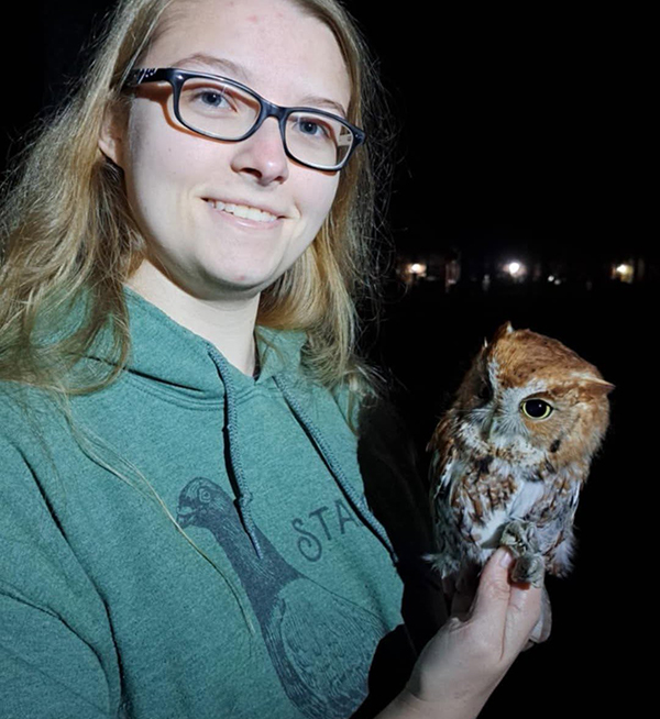 Wildlife student holding owl at night.
