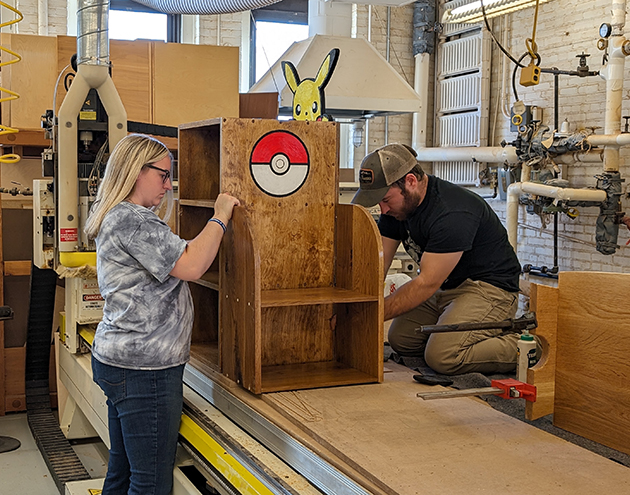 Student building wood shelf with help from lab technician.