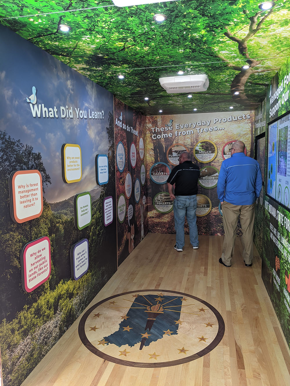 Woods on Wheels travel exhibit inside panels showing Indiana hardwoods with people reading the information.