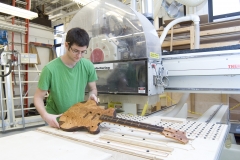 Student using shop tools to build guitar body.