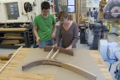 Student works with instructor on wooden furniture legs.