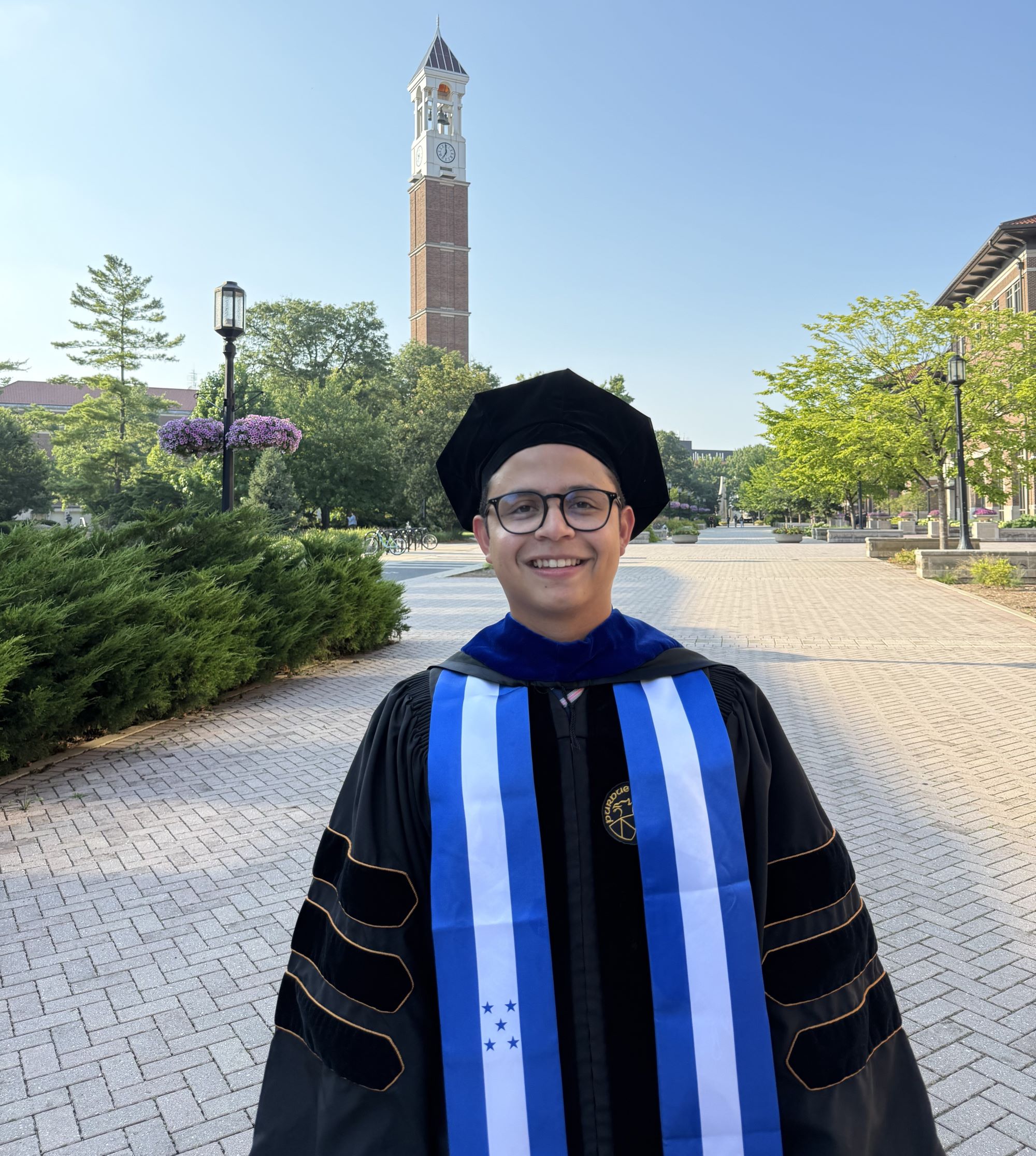 Edward Moncada in his graduation gown in front of the clock tower