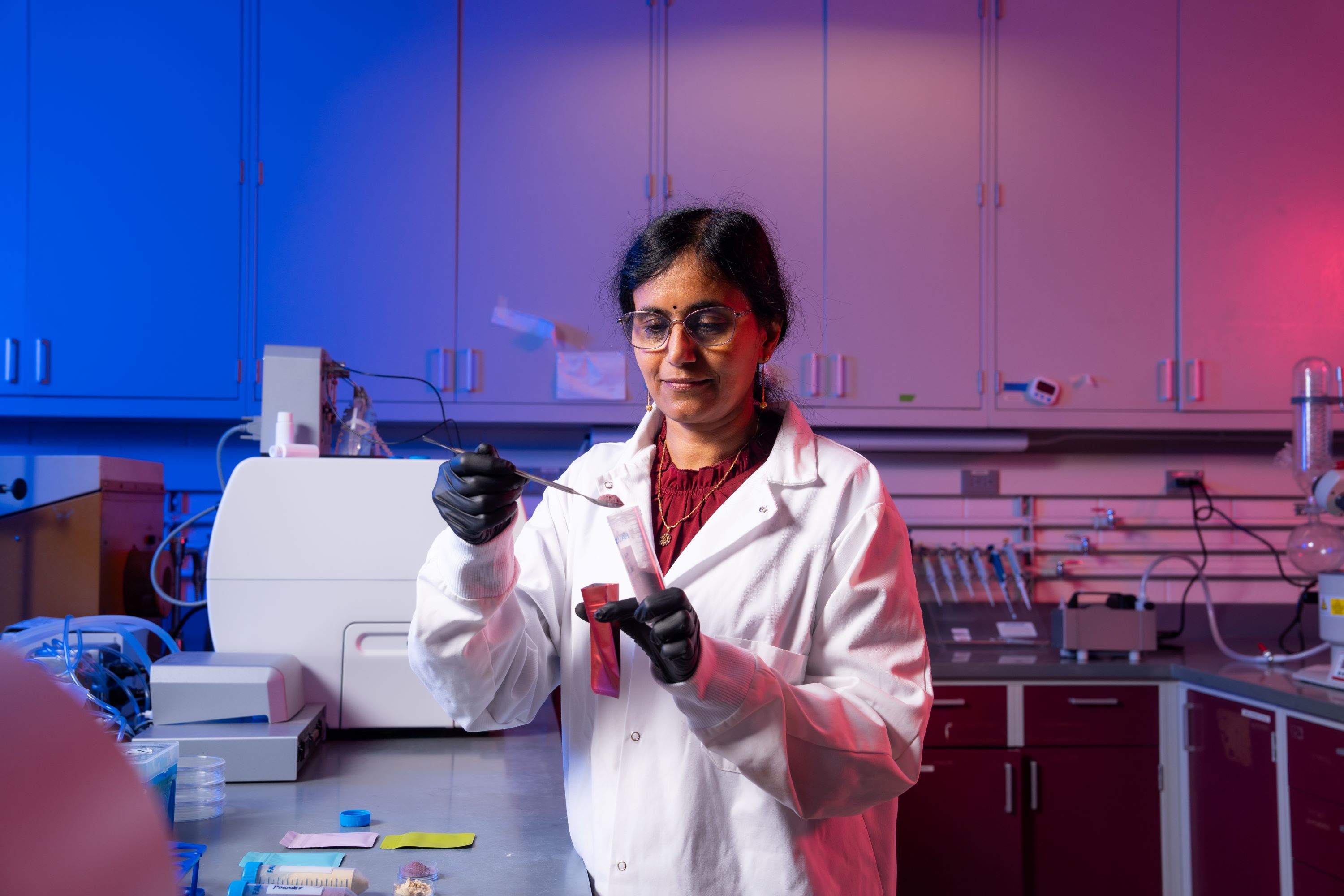 Professor in laboratory scooping berry powder to put in a test tube