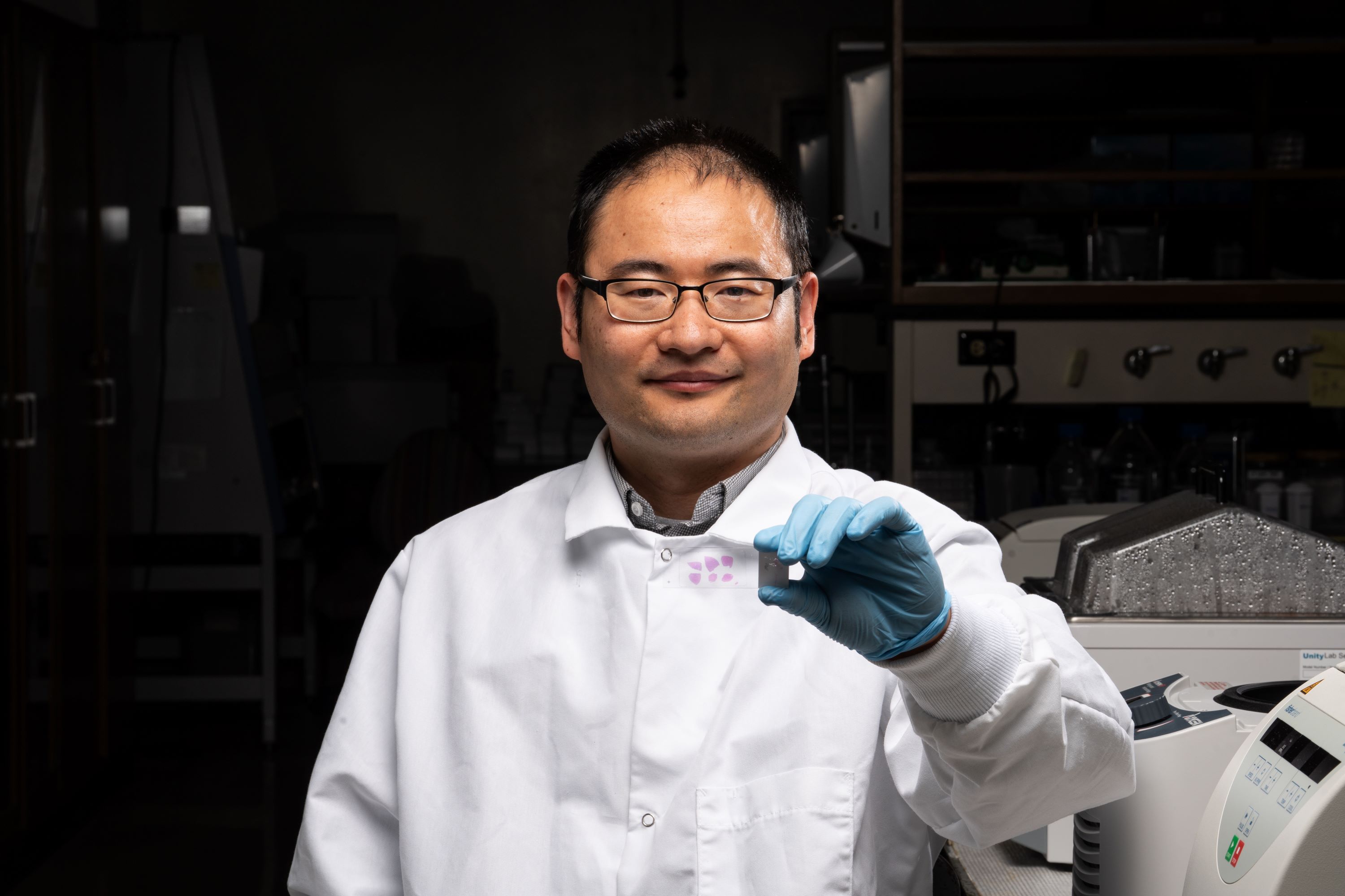 Weicang Wang holding a microscope slide
