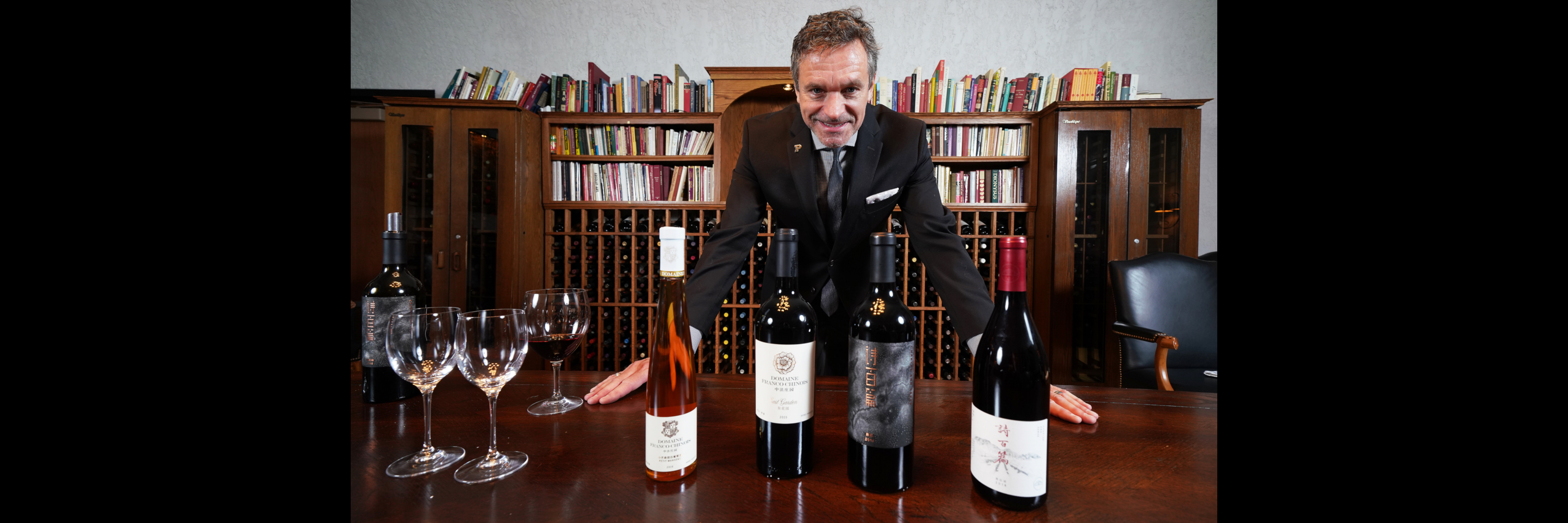 Instructor poses next to bottles of wine