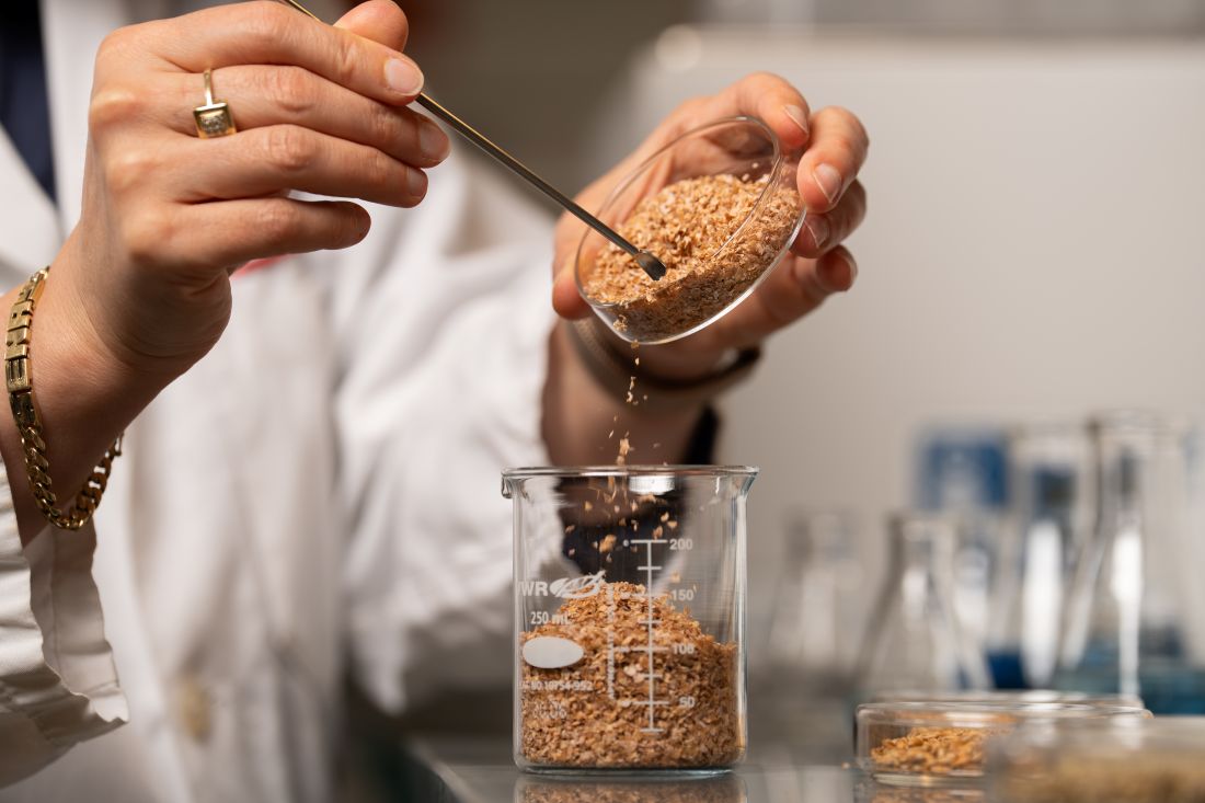 Researcher measuring grains in a beaker at lab bench