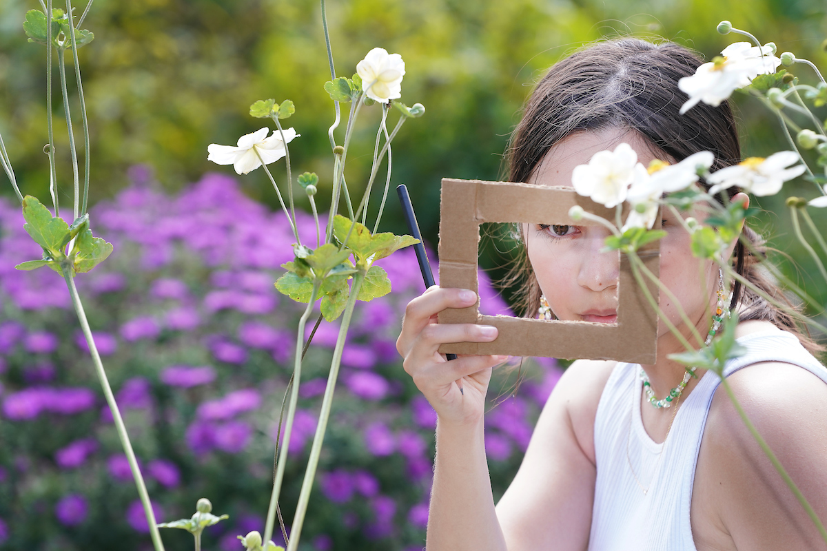 Student observing the garden through a rectangular cardboard cutout.