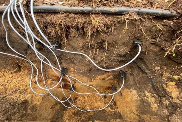 Soil profile cross-section with multiple soil moisture sensors installed at different depths and connected by wires to measure volumetric water content.