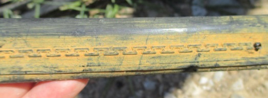 Drip irrigation tubing coated with reddish-brown iron deposits from mineral buildup.