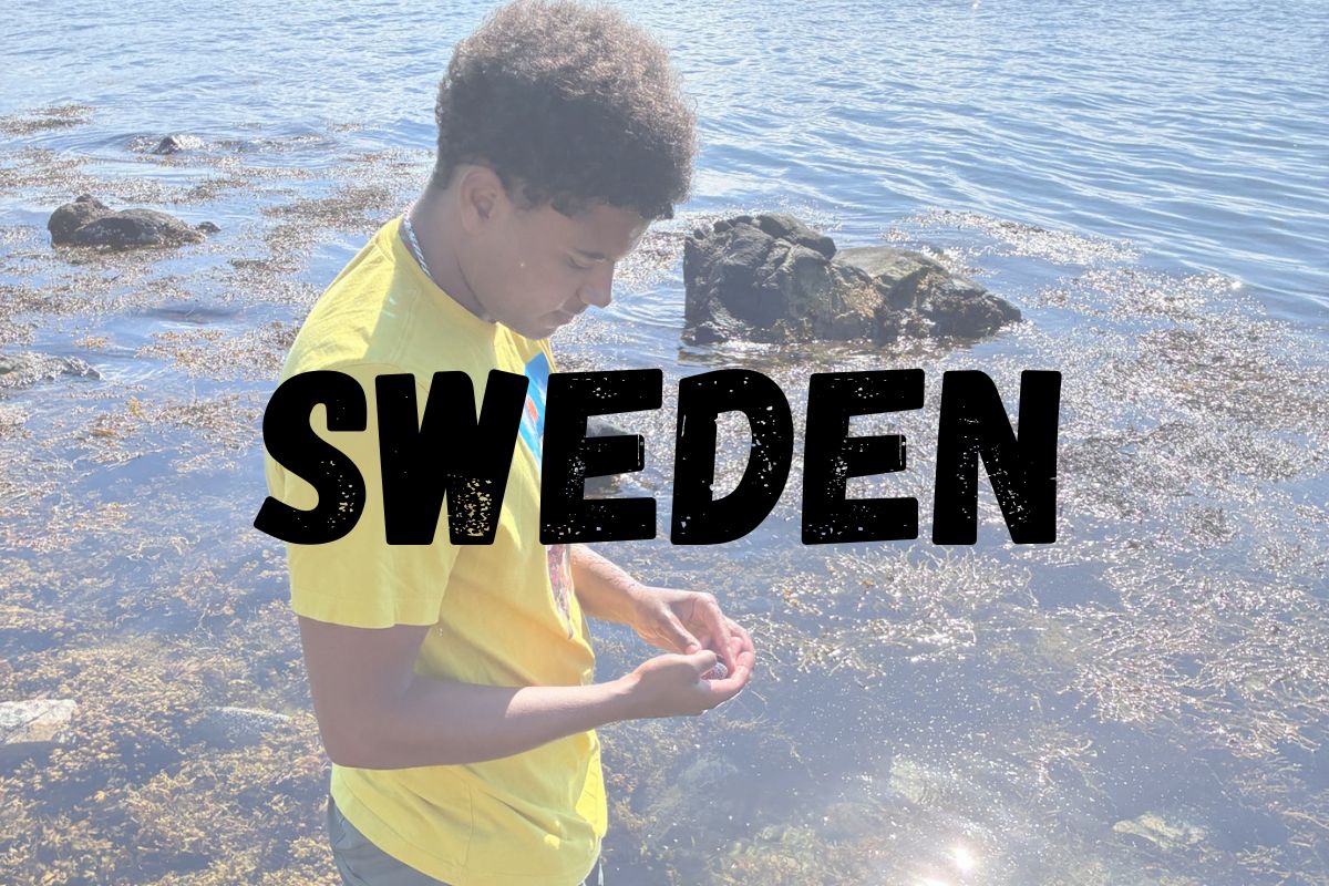 Student standing in water in Sweden with item from water