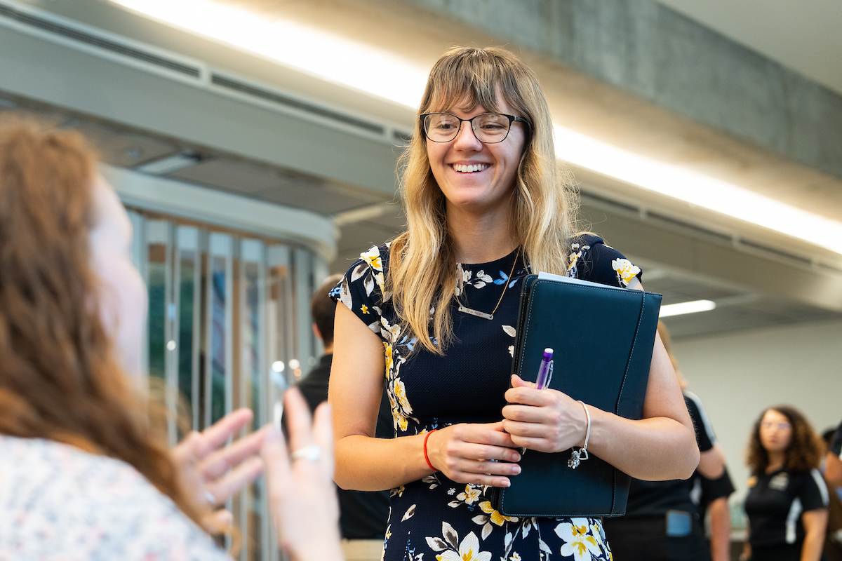 woman smiling holding a document folder