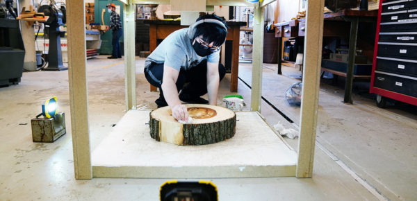 person working on a sliced piece of tree trunk