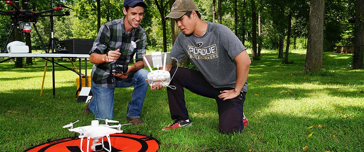 two peope with drone in a forest