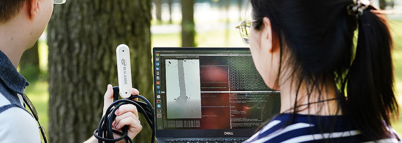 2 people outside looking at a laptop with a scanner in their hand