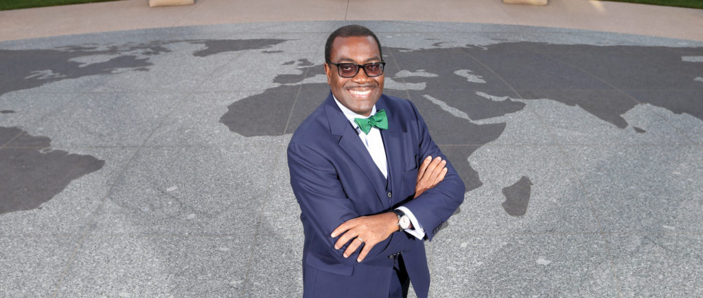 Akinwumi Ayodeji Adesina, president of the African Development Bank Group, stands with crossed arms on top of a stone world map