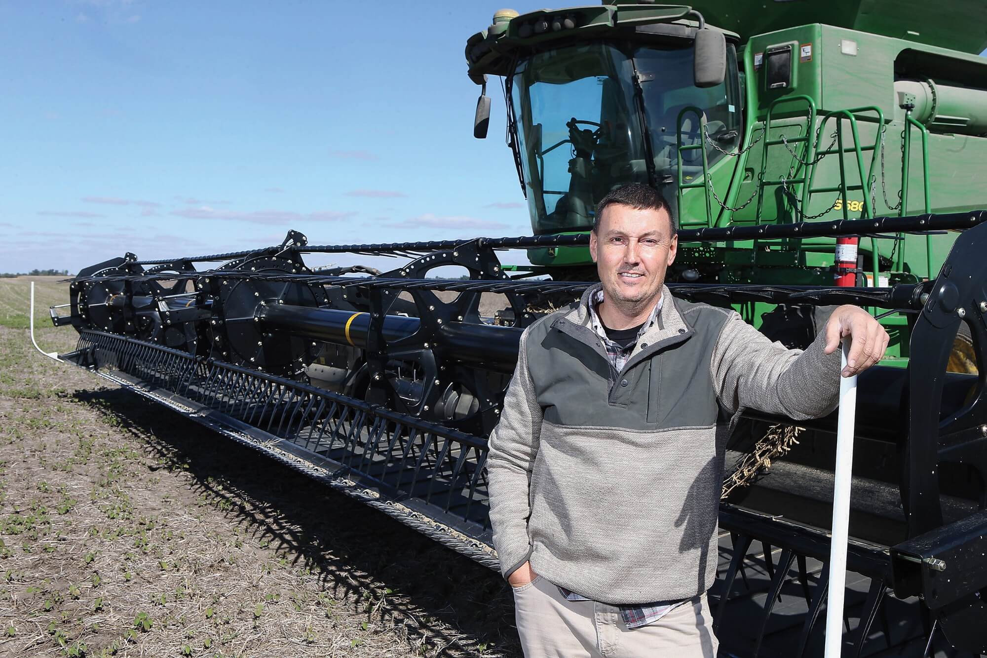 Brent Bible stands in front of a combine harvester in the field