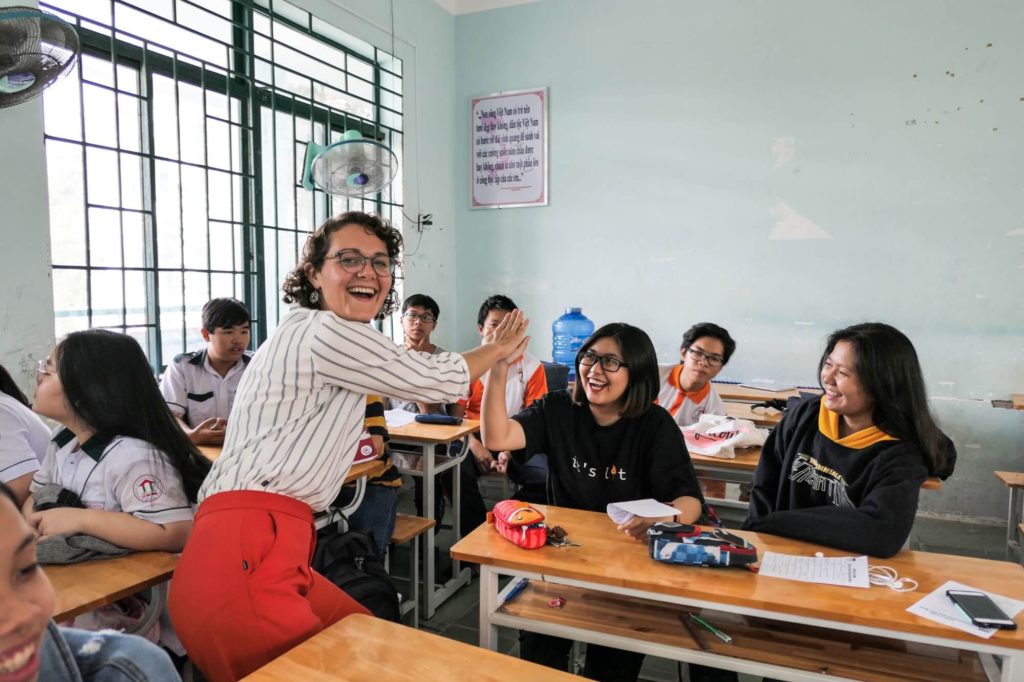 Chelsea Maupin high fives a student in a Vietnamese classroom