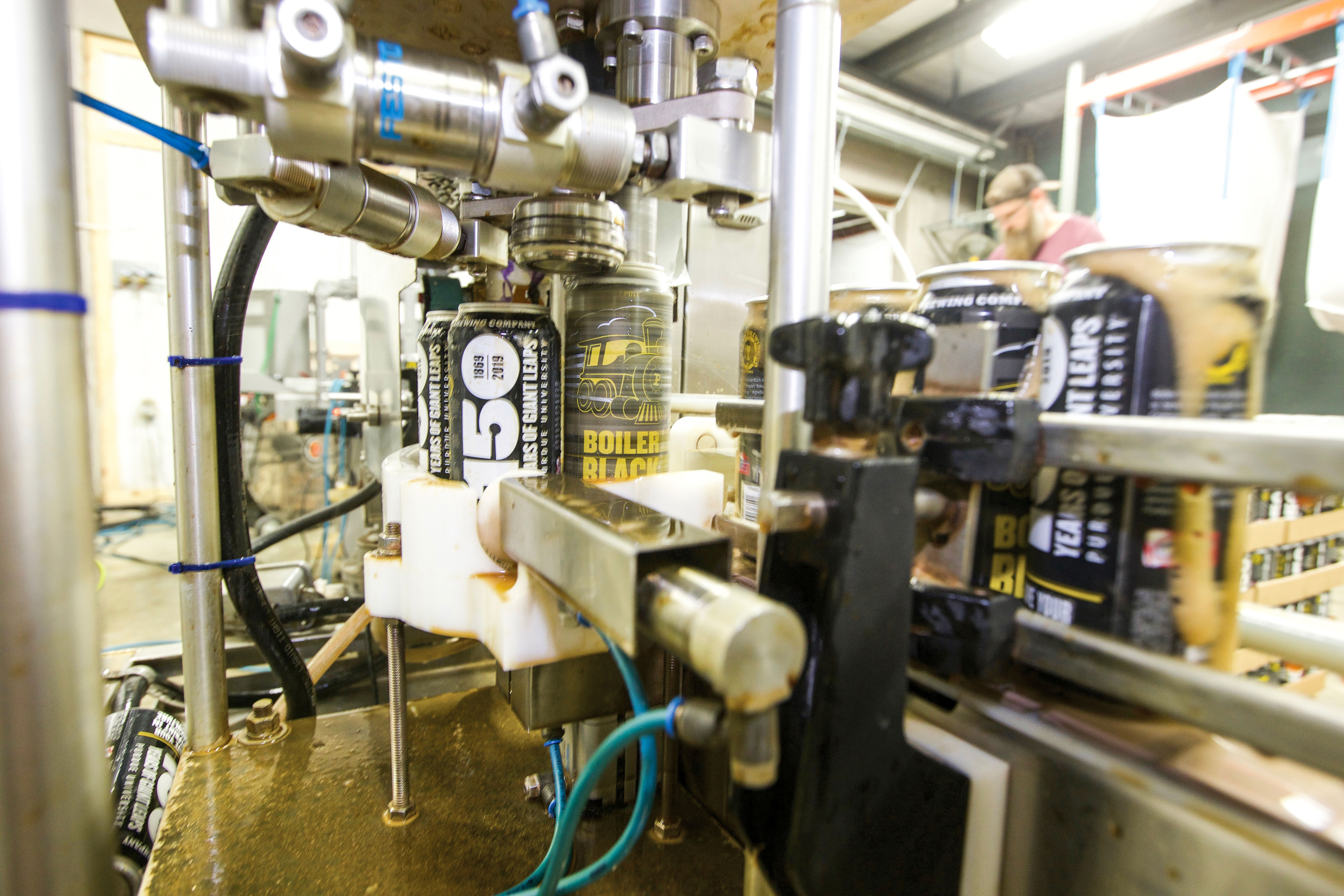 cans of Purdue Black beer are spinning off the line