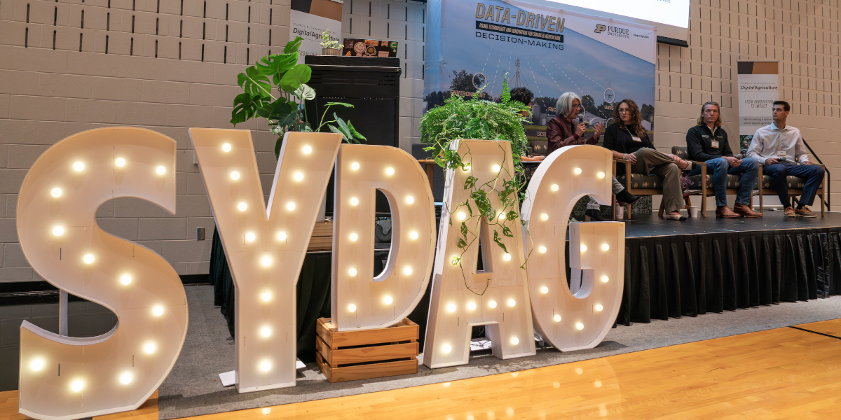 SyDAg 2025 Stage with Sign and Panelists