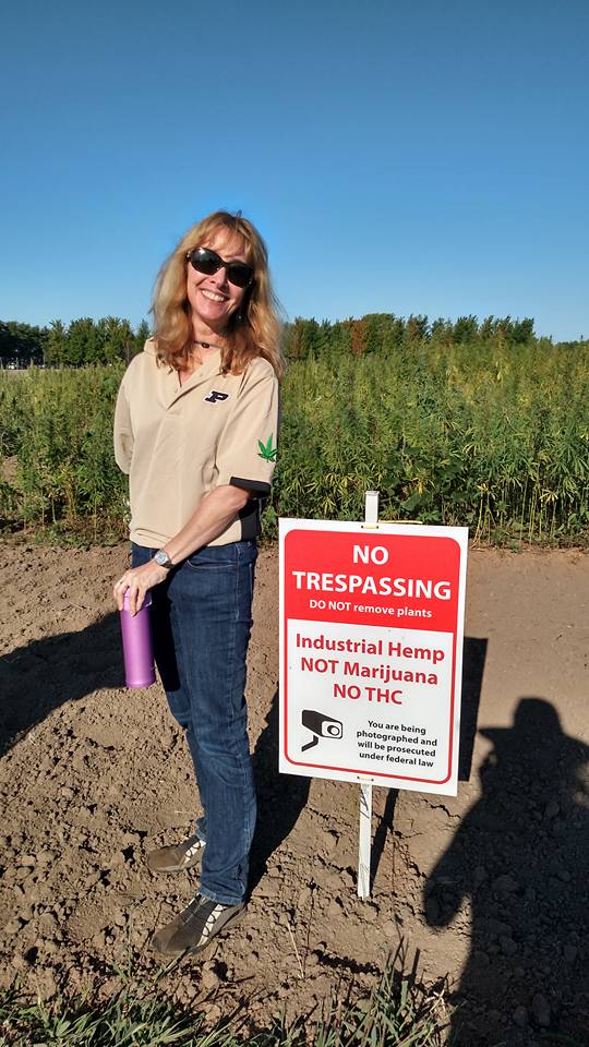 Purdue hemp researcher stands next to farm's no trespassing sign
