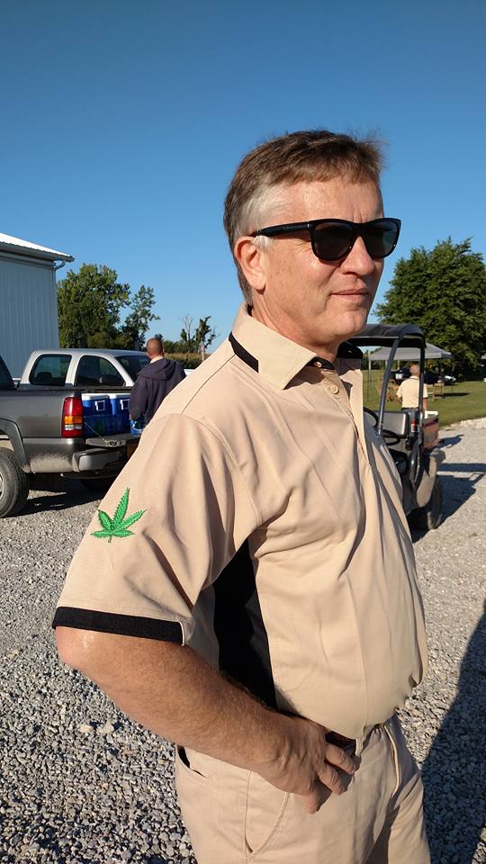 Purdue hemp researcher in tan uniform with hemp leaf logo on shoulder
