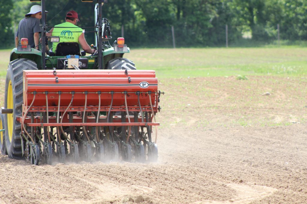 Image of a grain drill planting hemp seeds in soil. 