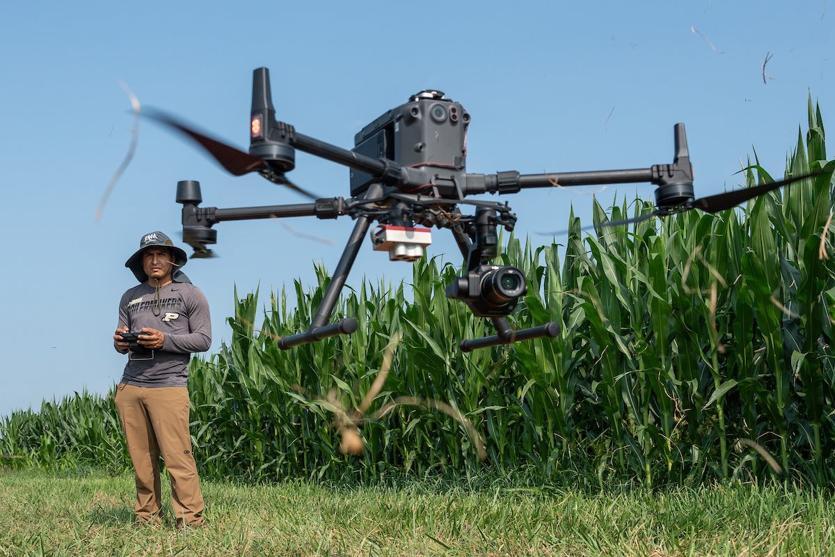 student flying a drone over a field