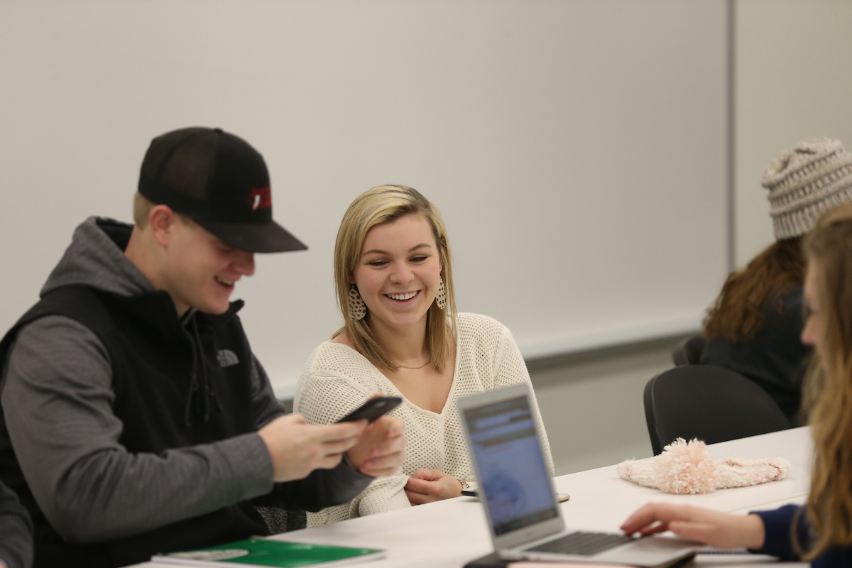 students checking data in a phone and in a laptop